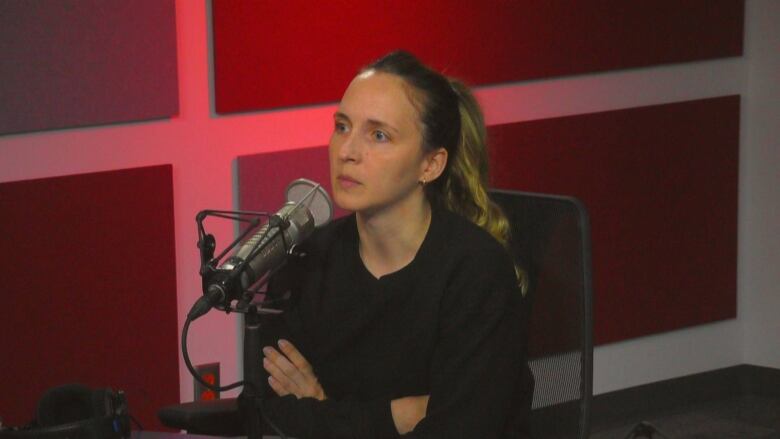 Person with dark blond hair pair pulled back wearing a dark shirt