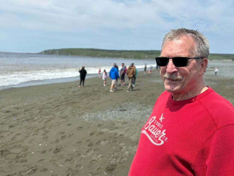 A man wearing a bright red sweater and sunglasses