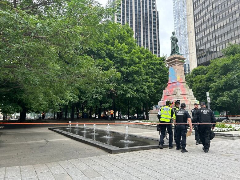 police in a square with graffiti on a monument. 