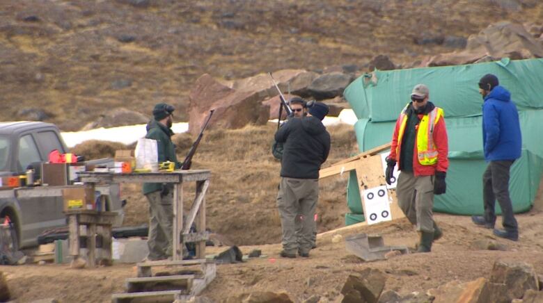 Shooters holding rifles at a shooting range