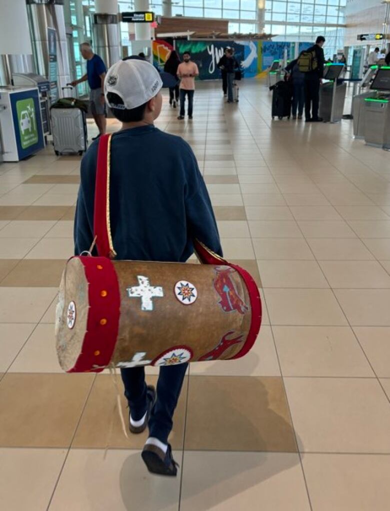 National Chief's son carries her headdress through the airport 