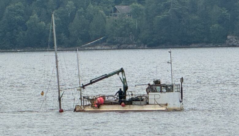 A barge next to two masts sticking straight out of the water. 