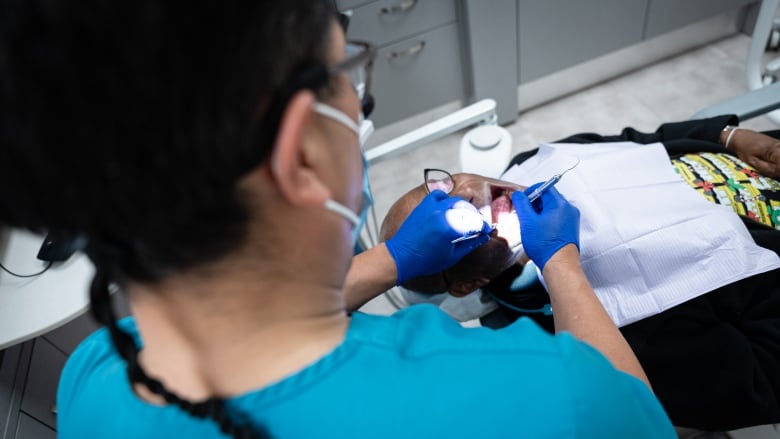 A dentist in Ottawa is seen examining the teeth of a patients in his clinic through the Canadian Dental Care Plan in May 2024.