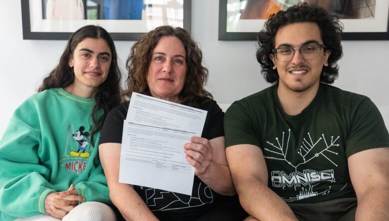 Priyanka Kashyap, Caroline Novak and Ashwin Kashyap sit side by side. Caroline, in the centre, holds up two parking ticket notices. 