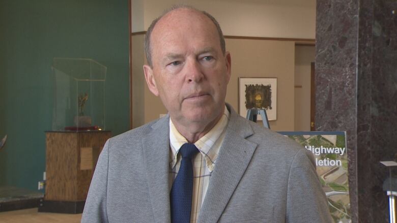 A man wearing a suit stands in the lobby of Confederation Building.