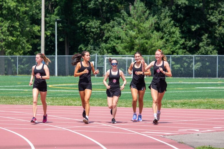 Five people run side-by-side on a track.