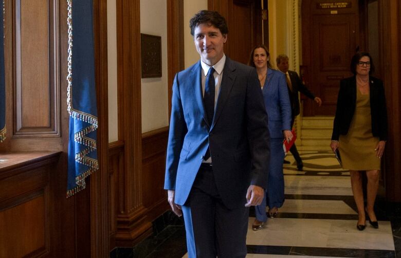 Trudeau walking in an elegant hallway, with Canada's ambassador Kirsten Hillman a few metres behind.