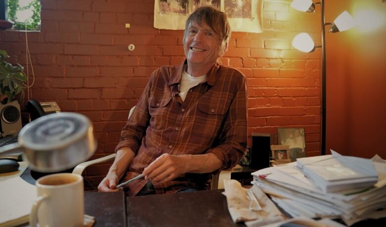 A man sits in an office and smiles. 