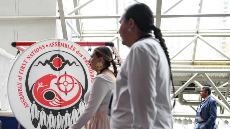 Attendees walk past a banner  at the Assembly of First Nations annual general assembly  in Montreal, Tuesday, July 9, 2024.