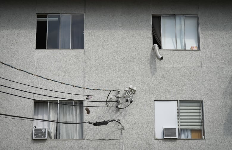 Window air conditioner units seen from the exterior of an apartment building. 