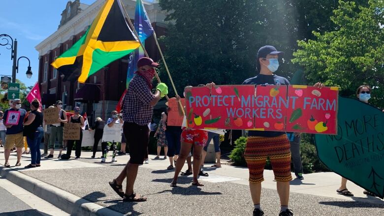 See masked protester holding sign that reads: 