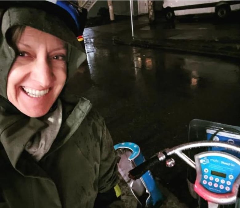 A woman smiles beside a Mobi bike