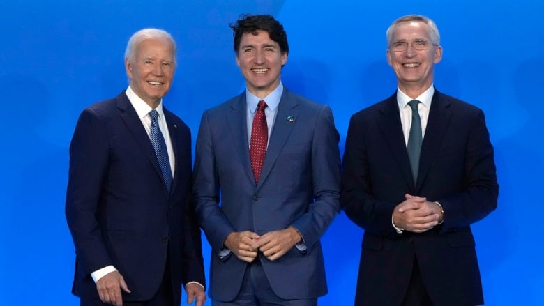 Three men wearing suits smile for the camera.