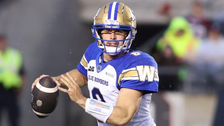 A football player in a blue and white jersey holds a ball