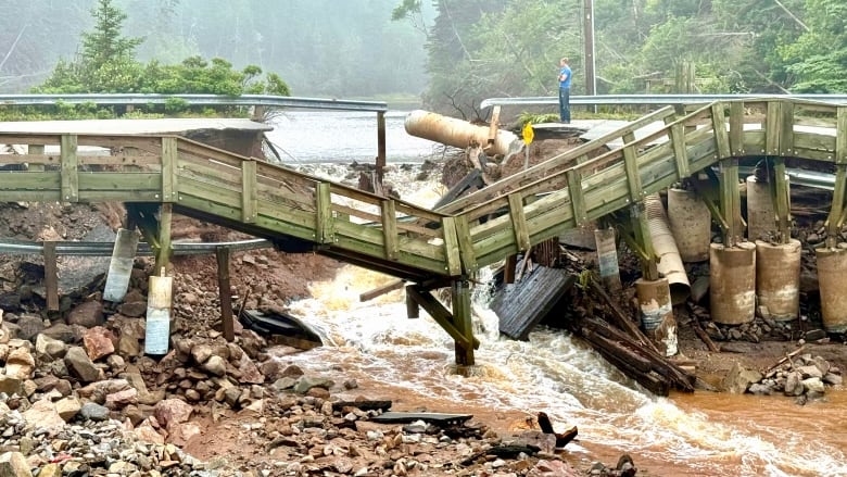 Brown water rushes through a collapsed bridge