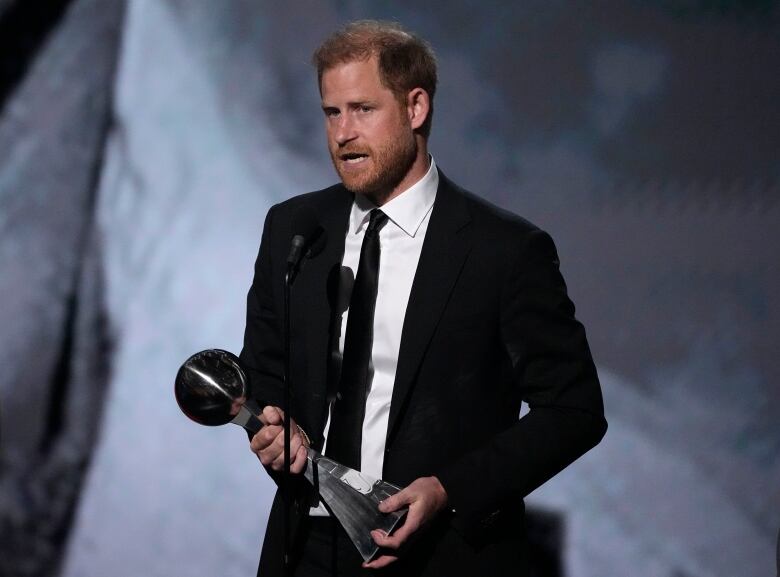 A person speaks while holding an award.