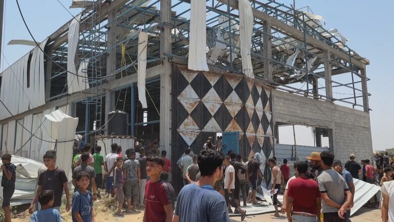 people walk by a destroyed building 