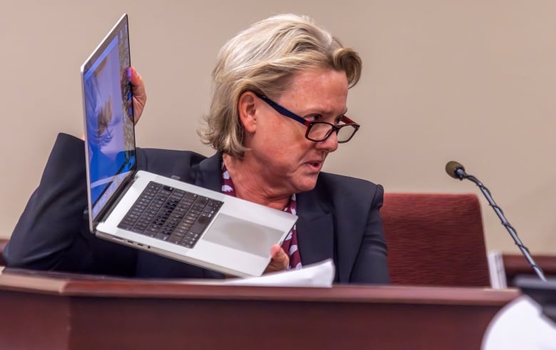 A person holds up an opened laptop.