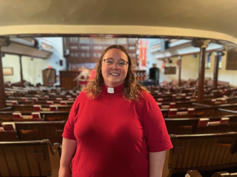 A person in a red shirt stands in a church.