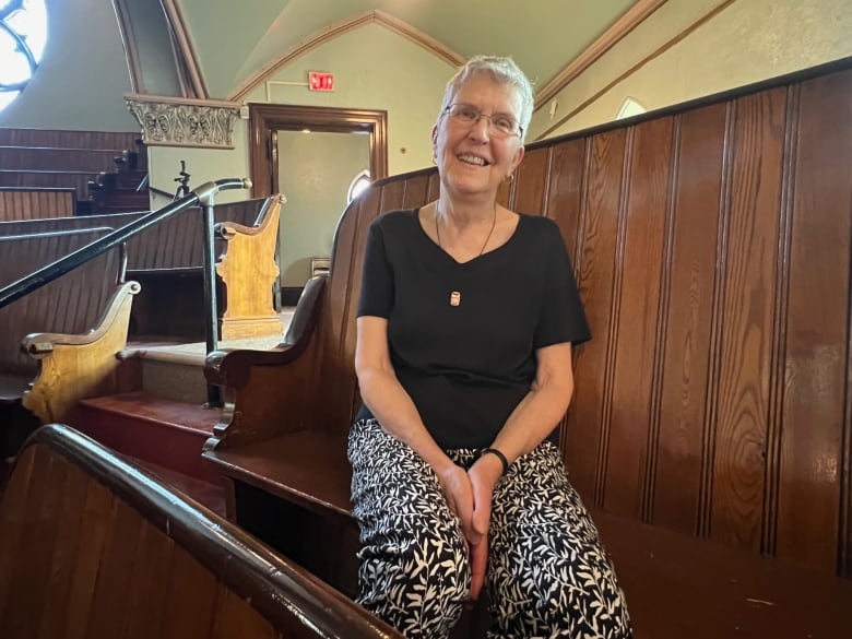 A person smiles while sitting in a church pew.