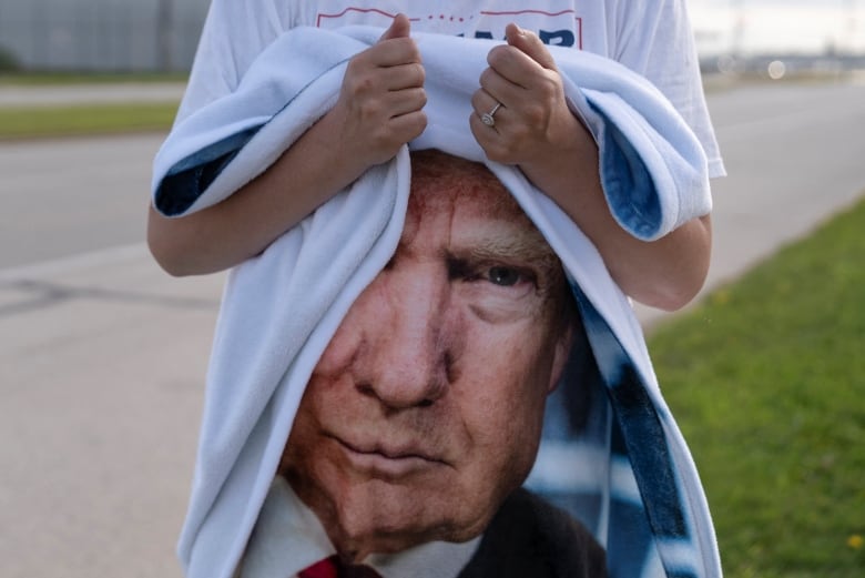 Woman holds cloth with Trump's face on it.