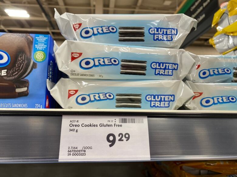 A stack of three white packages of gluten -free Oreos are seen on a store shelf with a price tag of $9.29.