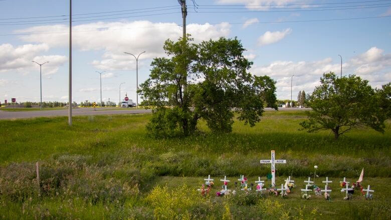 a memorial with multiple crosses by a highway.