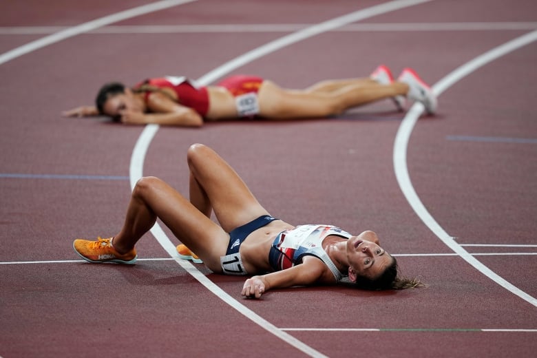 Two people lay on a running track after a race.