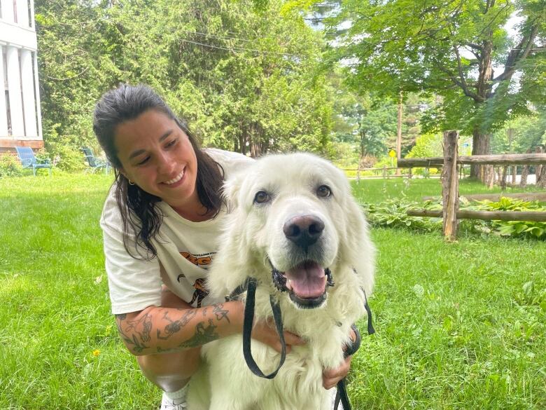 A woman smiles at the camera with her blonde dog. 