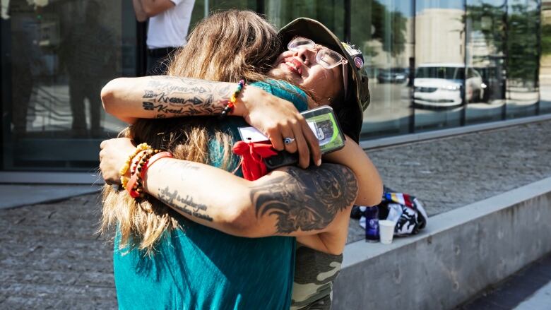 Two people in an emotional embrace outside a courthouse.