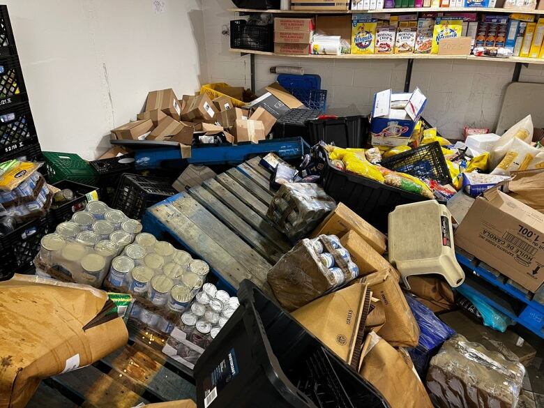 Piles of packaged food lie damaged on the floor of a food bank. The floor isn't visible.