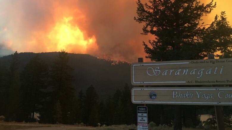 A sign that reads Saranagati Village, with flames in the background.