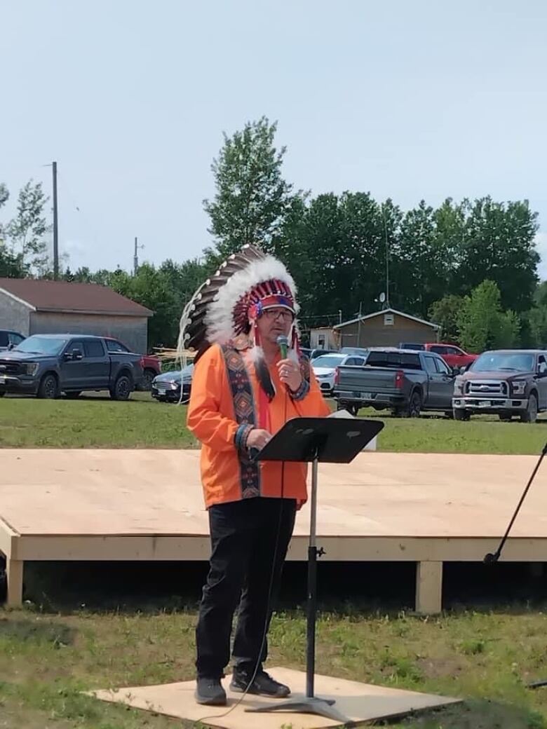 Man in headdress at podium.