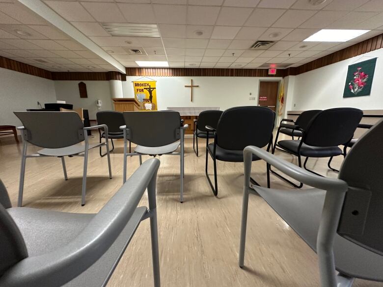 Chairs are shown in a room with an altar and Christian cross.