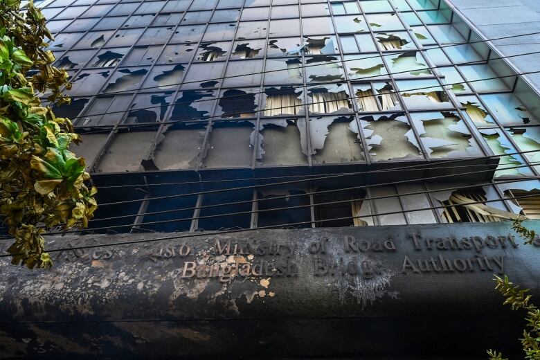 A burnt building with a sign reading 'Bangladesh Bridge Authority' is pictured.