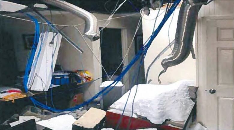 A heavily damaged office with a hole in the roof and a large pile of snow inside.