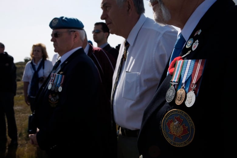 Canadian retired Major General Alain Forand, centre, joined by fellow veteran soldiers who served with the United Nations Peacekeeping force on war-divided Cyprus, listen to details of battles that took place 40 years ago on the fringes of the disused Nicosia airport located inside the UN-controlled buffer zone on the capital's outskirts on Tuesday, March 18, 2014.