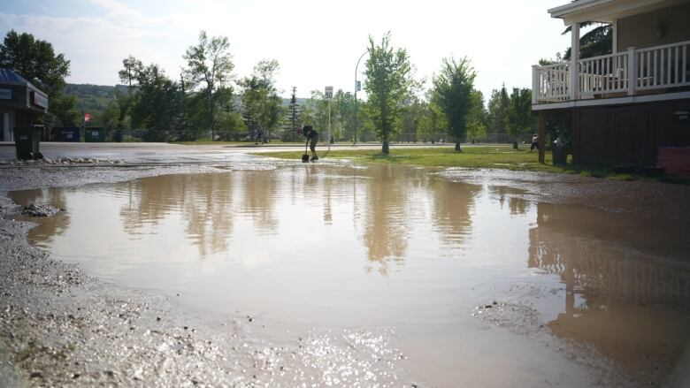 a pool of muddy water in a parking lot by a road.