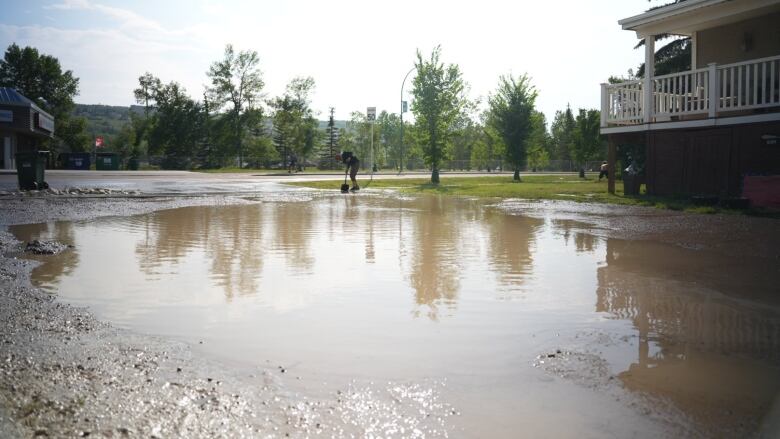 a pool of muddy water in a parking lot by a road.