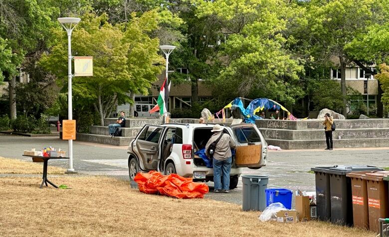 A patch of brown grass, some scattered tents, and a van.