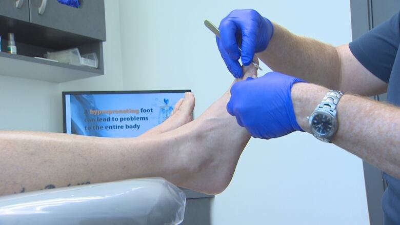 A foot is shown with a podiatrist's hand examining the toes. 