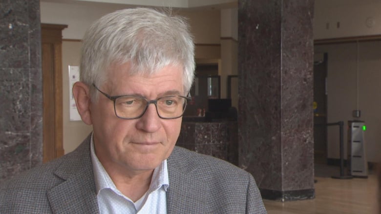 Man with white hair in grey suit