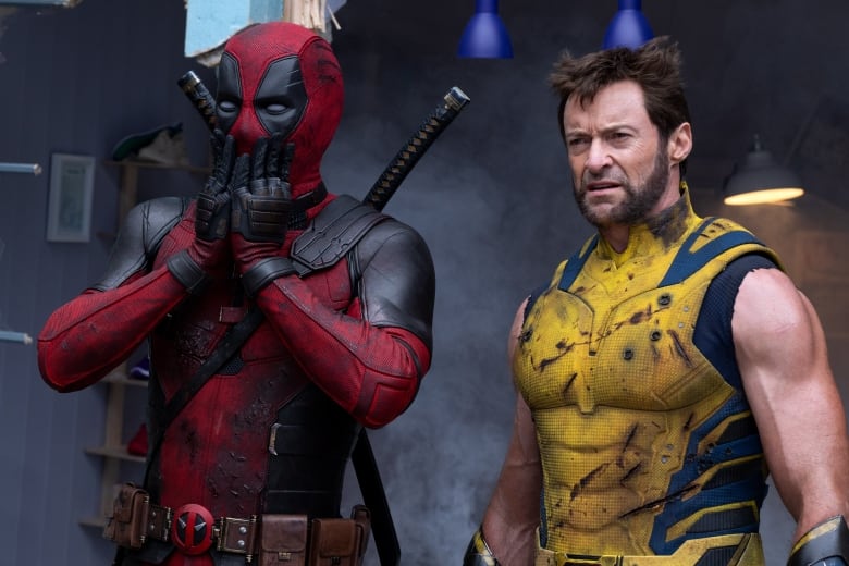 Ryan Reynolds dressed as Deadpool, looking surprised on the left, and Hugh Jackman dressed as Wolverine on the right, staring off-screen.