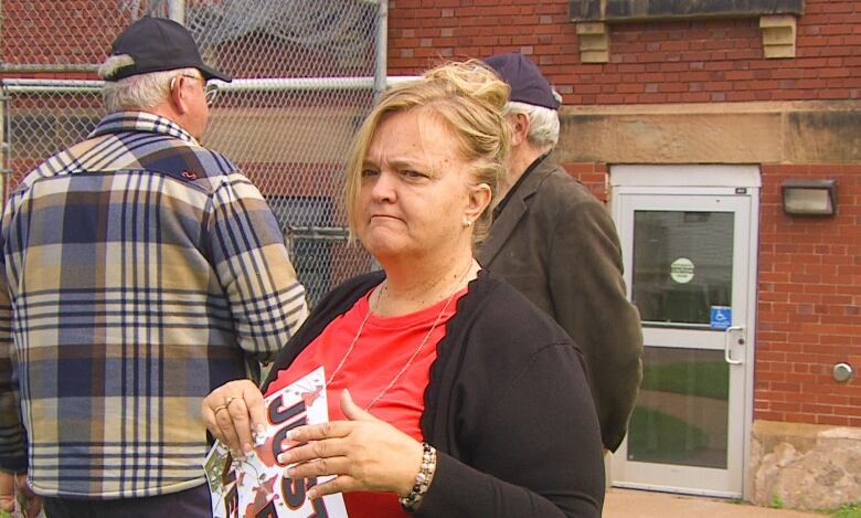 Woman holding sign outside court.