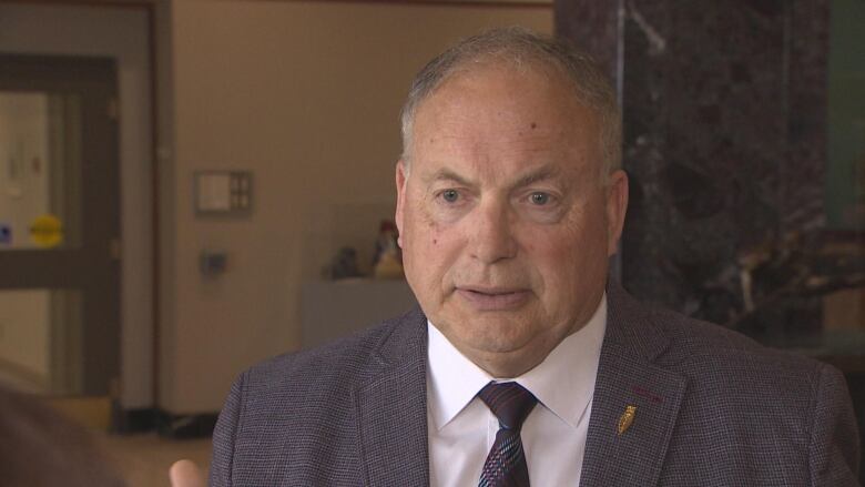 A man wearing a suit stands in the lobby of Confederation Building.