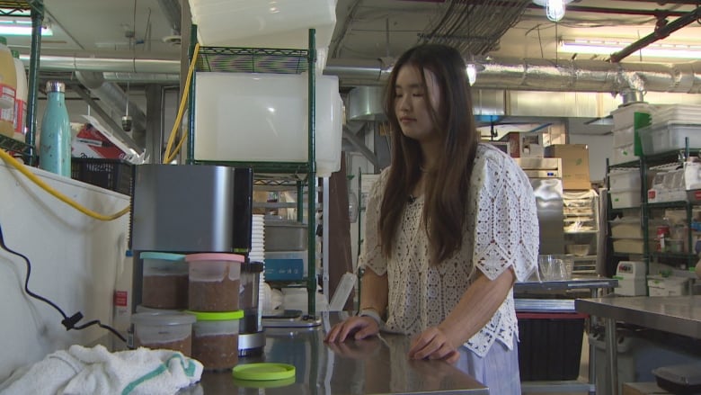 A woman looks at an ice cream machine in an industrial kitchen. 