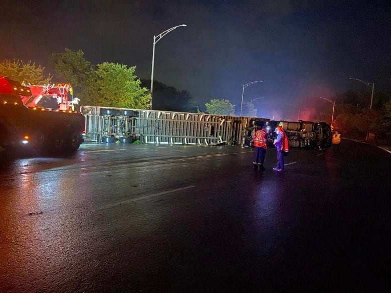 An overturned semi-trailer lying in the road at night. 