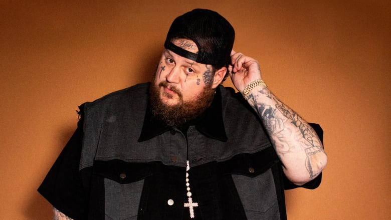 Portrait of Jelly Roll posing against a brown backdrop.