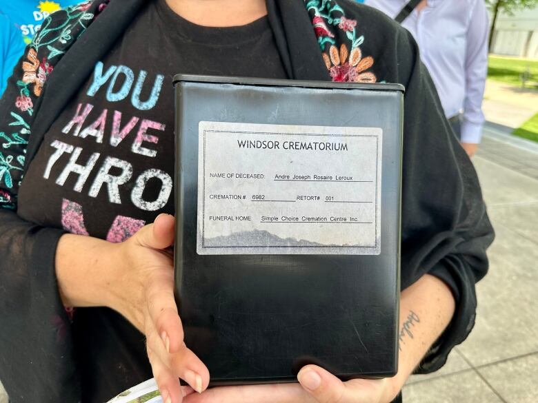 Ashes of a deceased person contained in a box, held by a loved one.