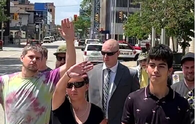 A man in a suit is surrounded by supporters near a courthouse.